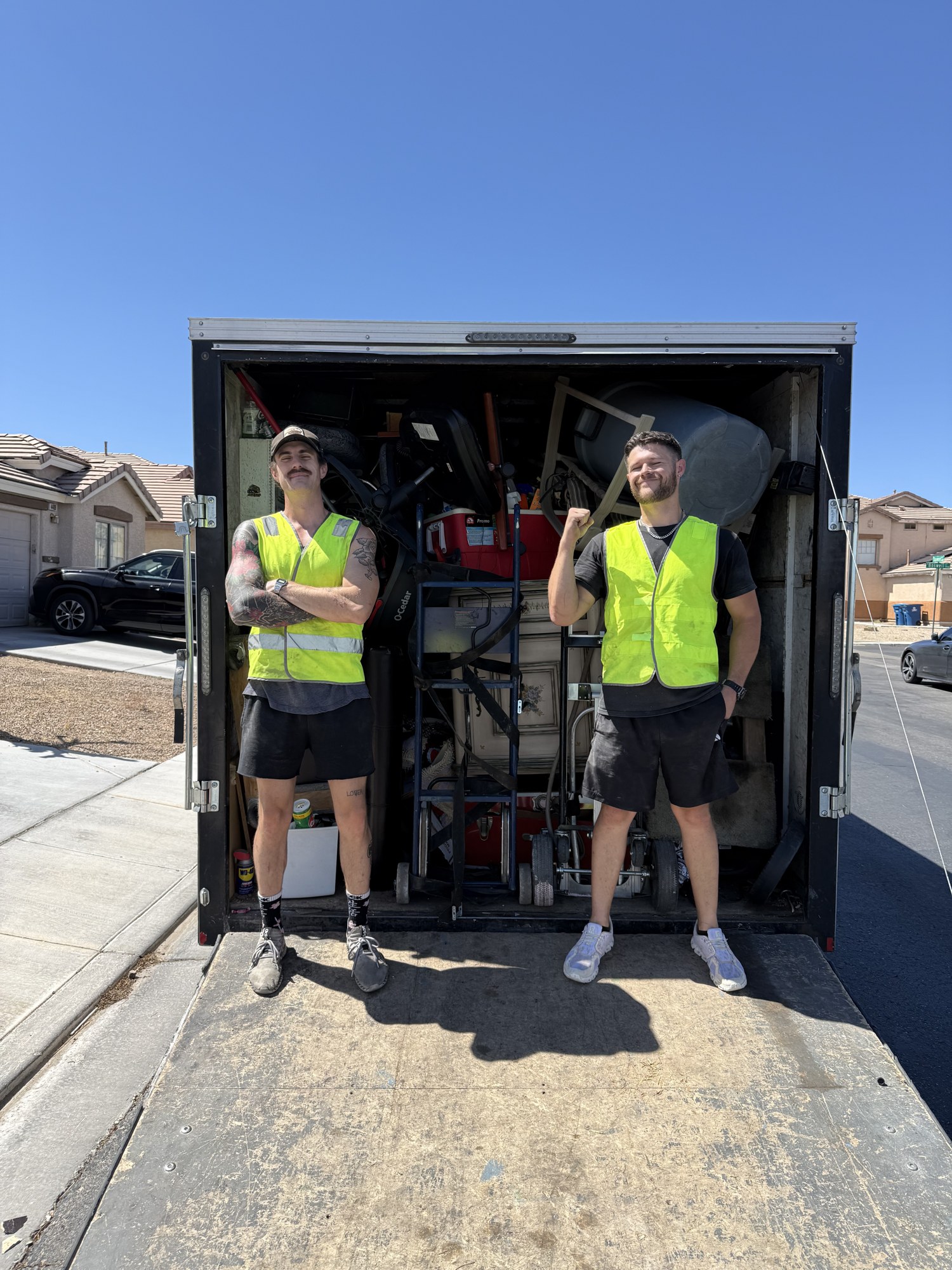 Two Haul It All team members beside a loaded hauling trailer